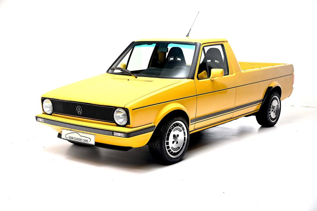 Classic yellow Volkswagen Caddy Mk1 pickup truck, exterior shot.