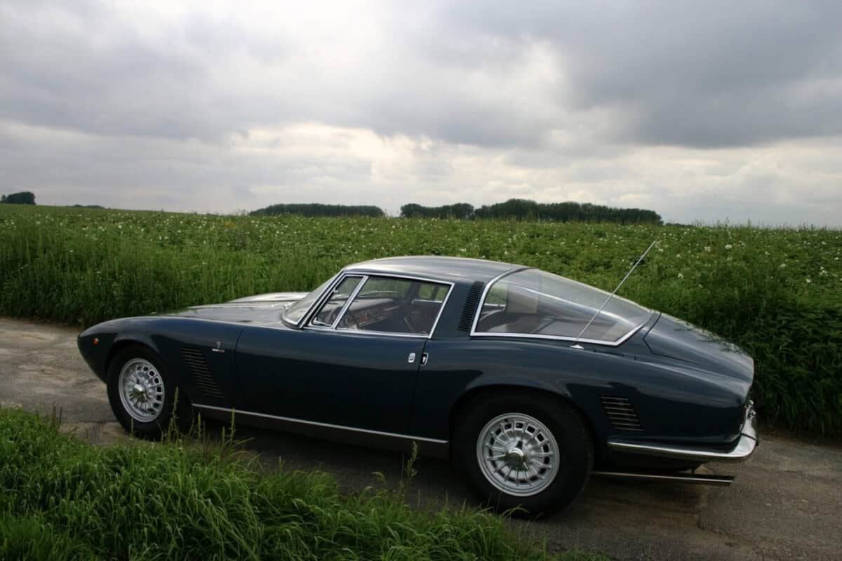 Side view of a classic blue vintage car parked on a rural road.