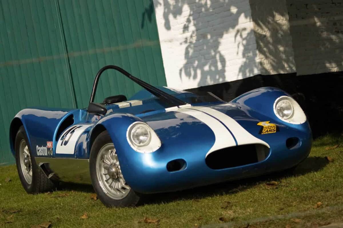 A blue vintage race car with white racing stripes, exterior view.