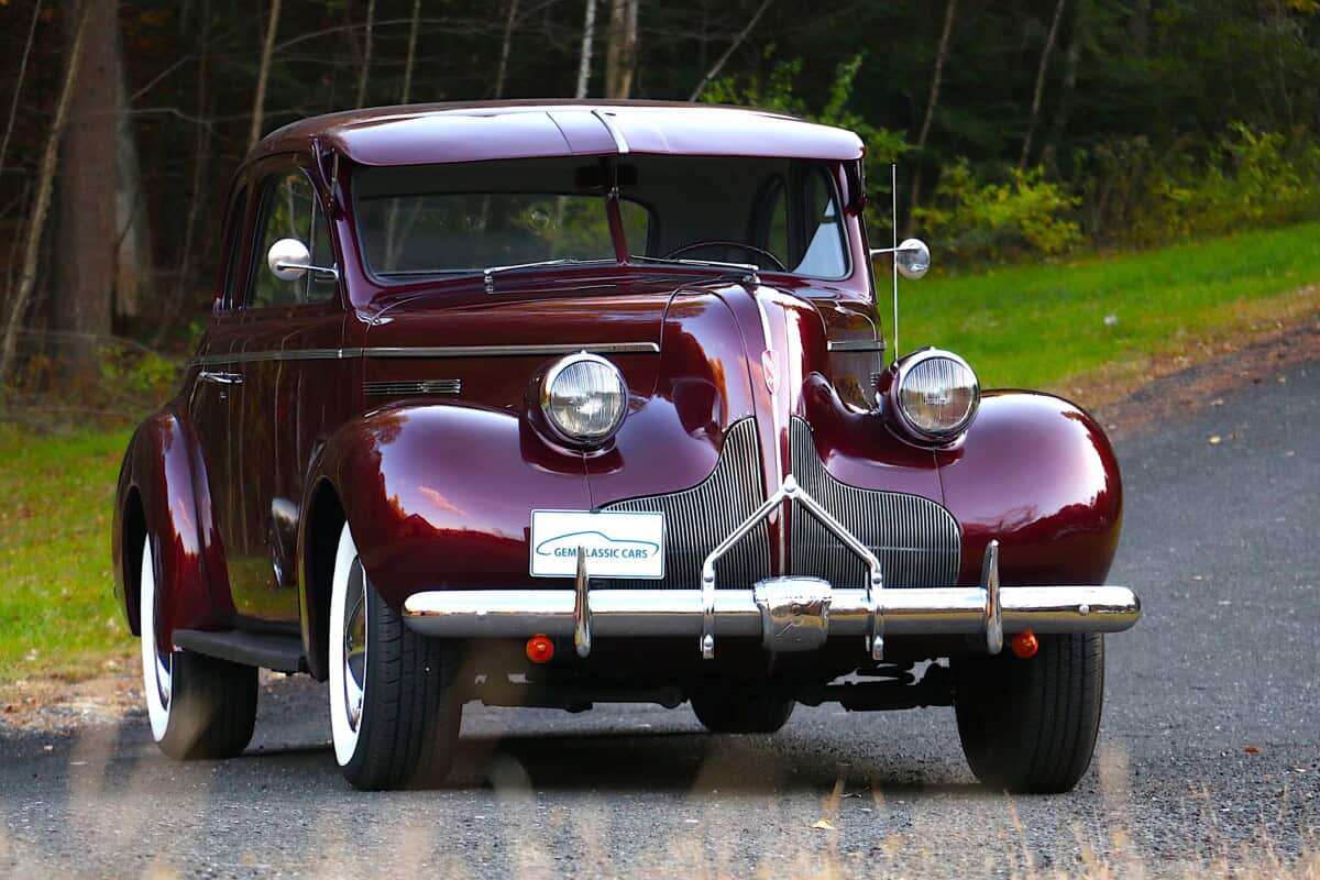 Classic car with maroon paint, chrome bumpers, and round headlights.
