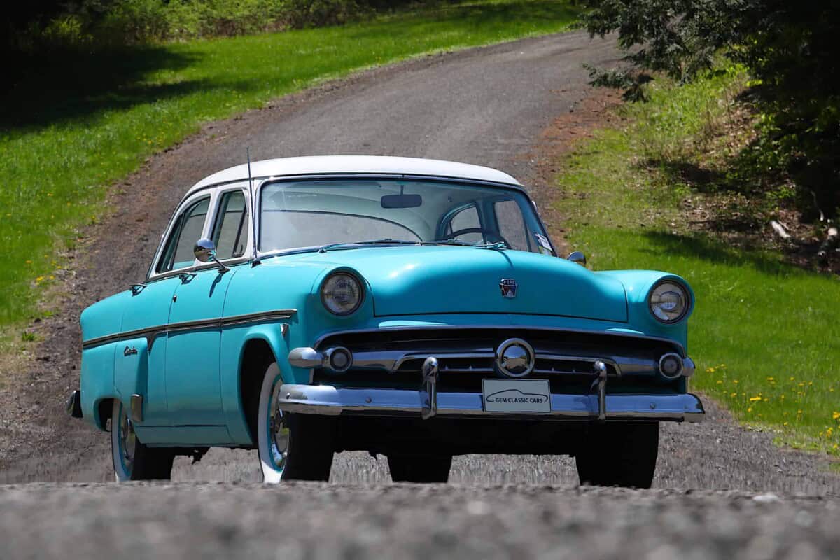 Exterior shot of a vintage blue classic car on a gravel path.