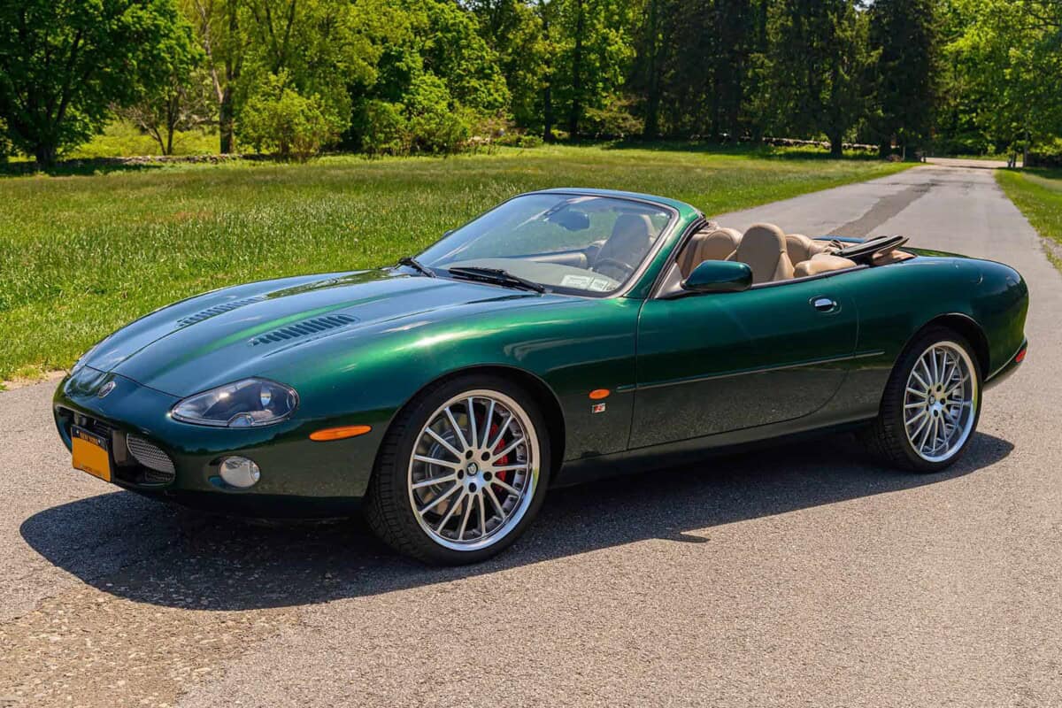 Green convertible sports car parked on a country road, exterior view.