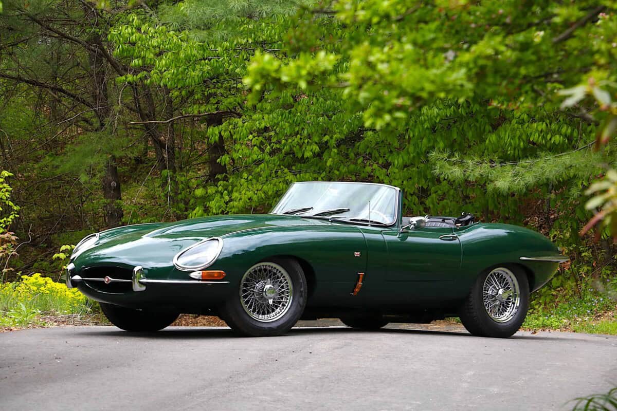 Exterior shot of a classic green Jaguar E-Type convertible parked outdoors.