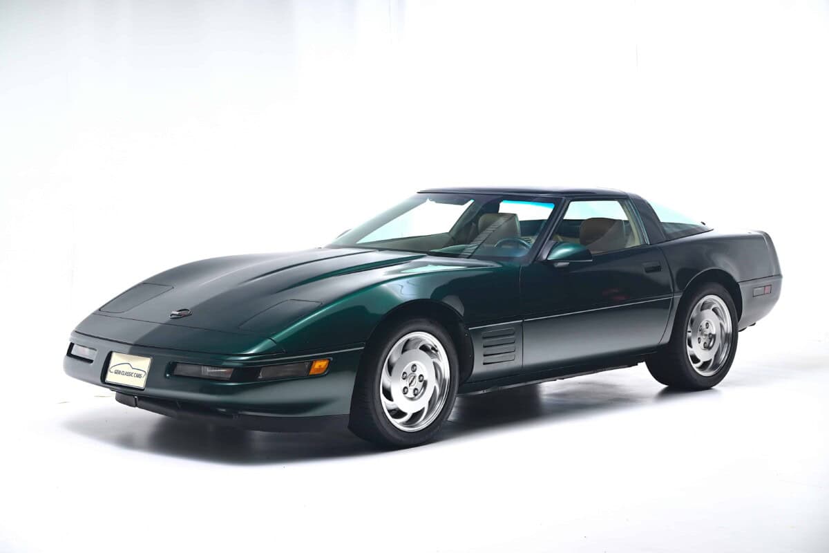A sleek green Corvette C4 sports car photographed from the side in a studio sett.