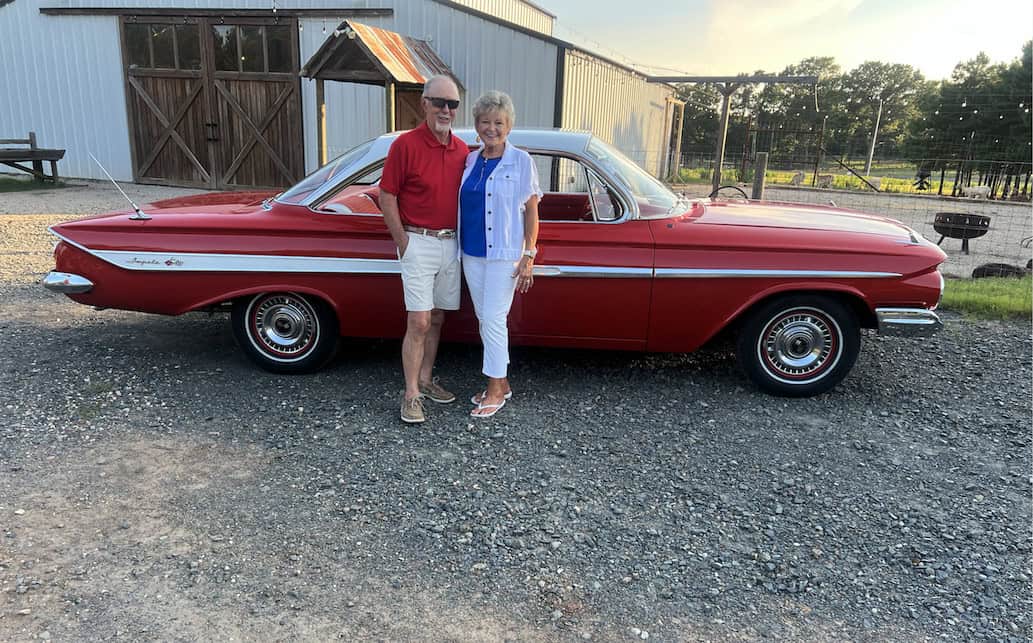 1961 Chevrolet impala — Exterior shot of a classic car with a man and woman standing beside it.