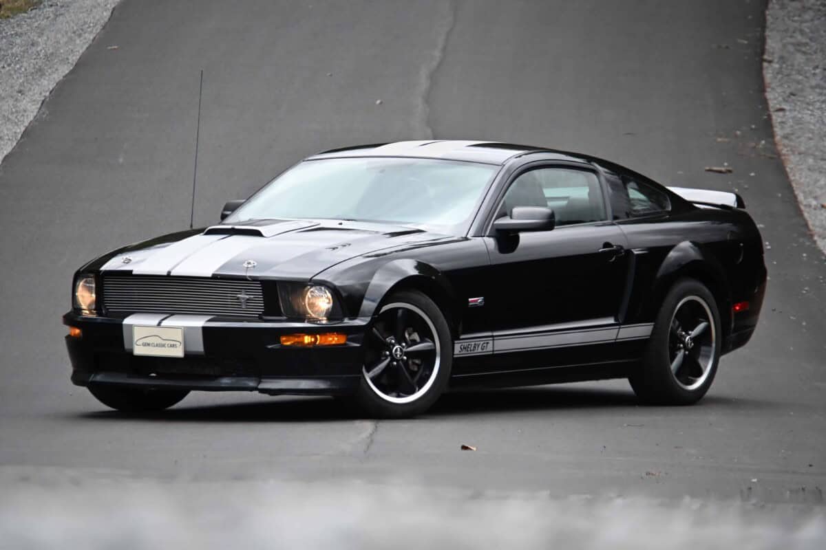 Side view of a black Ford Mustang sports car on the road.