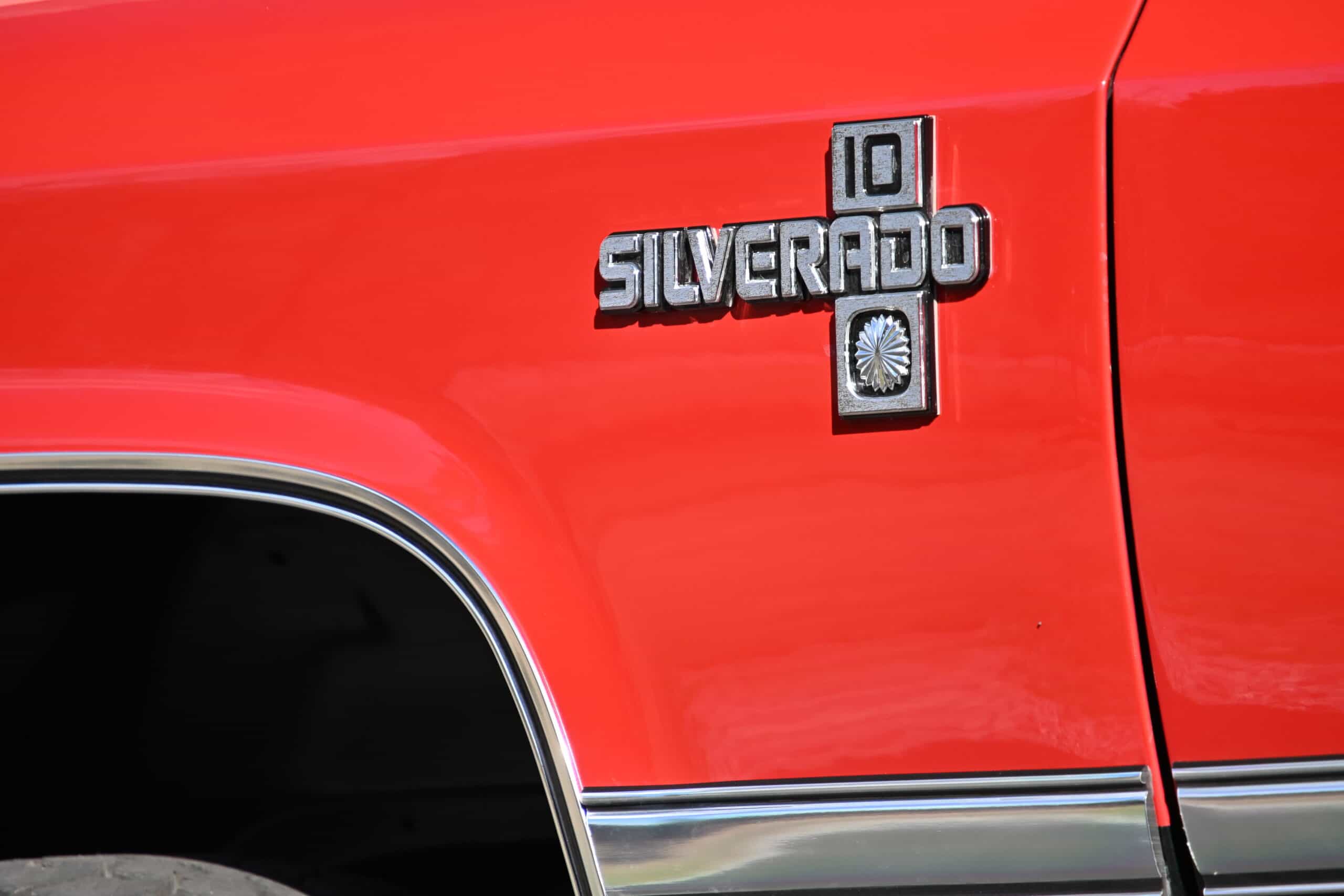 1986 Chevrolet SILVERADO — Close-up of classic car side with emblem and chrome trim.