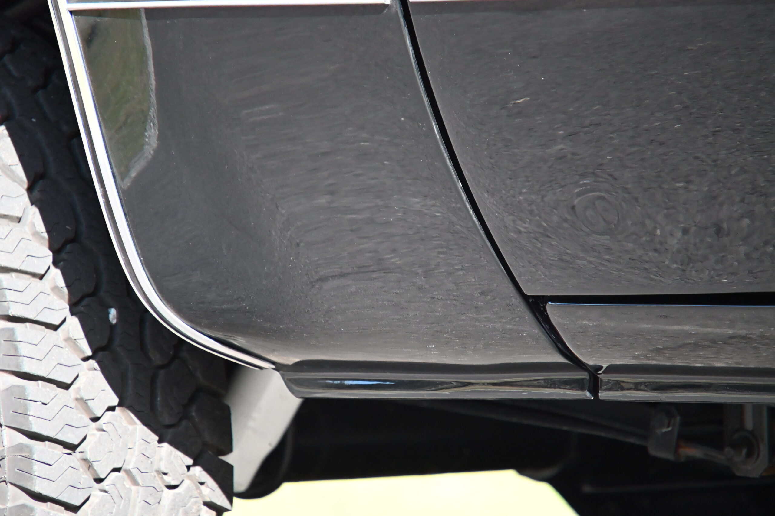 1986 Chevrolet SILVERADO — Close-up of black classic car body and tire tread.
