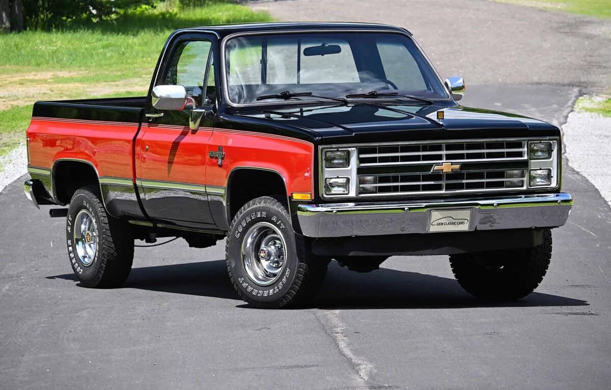 Classic car pickup truck with black and red body, chrome details.