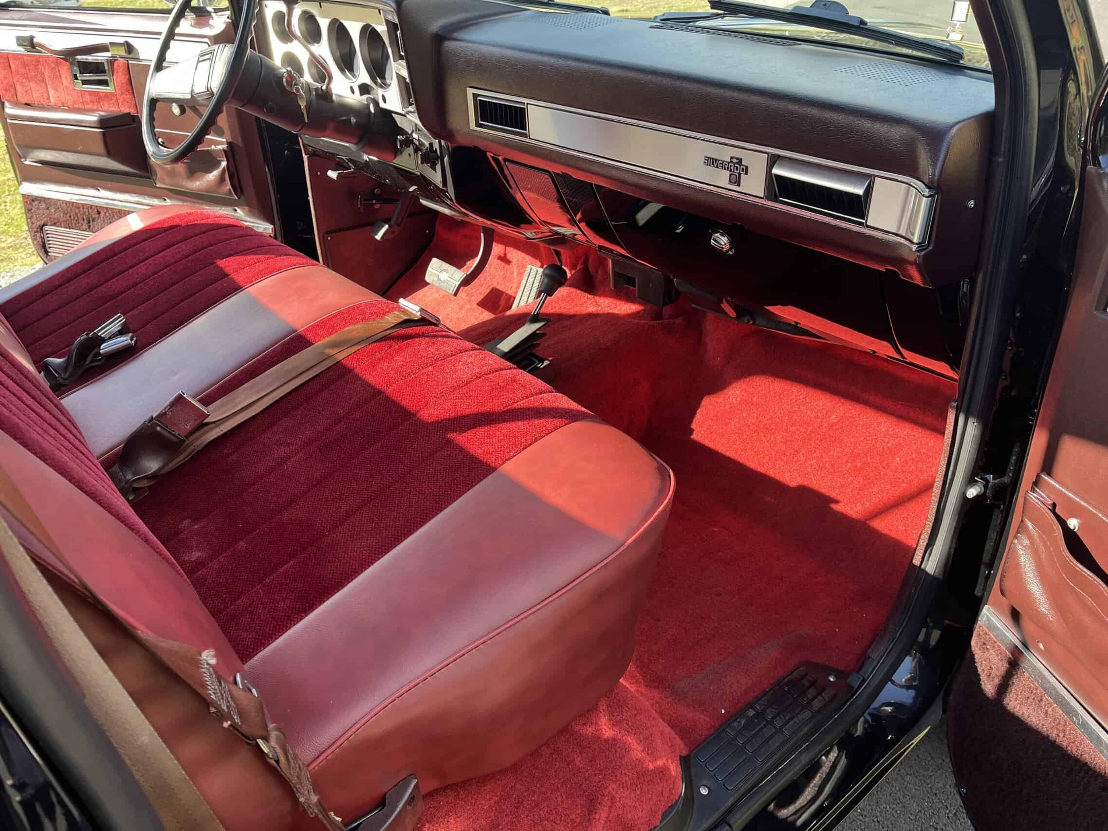 1986 Chevrolet SILVERADO — Interior shot of a classic car with red seats and dashboard.