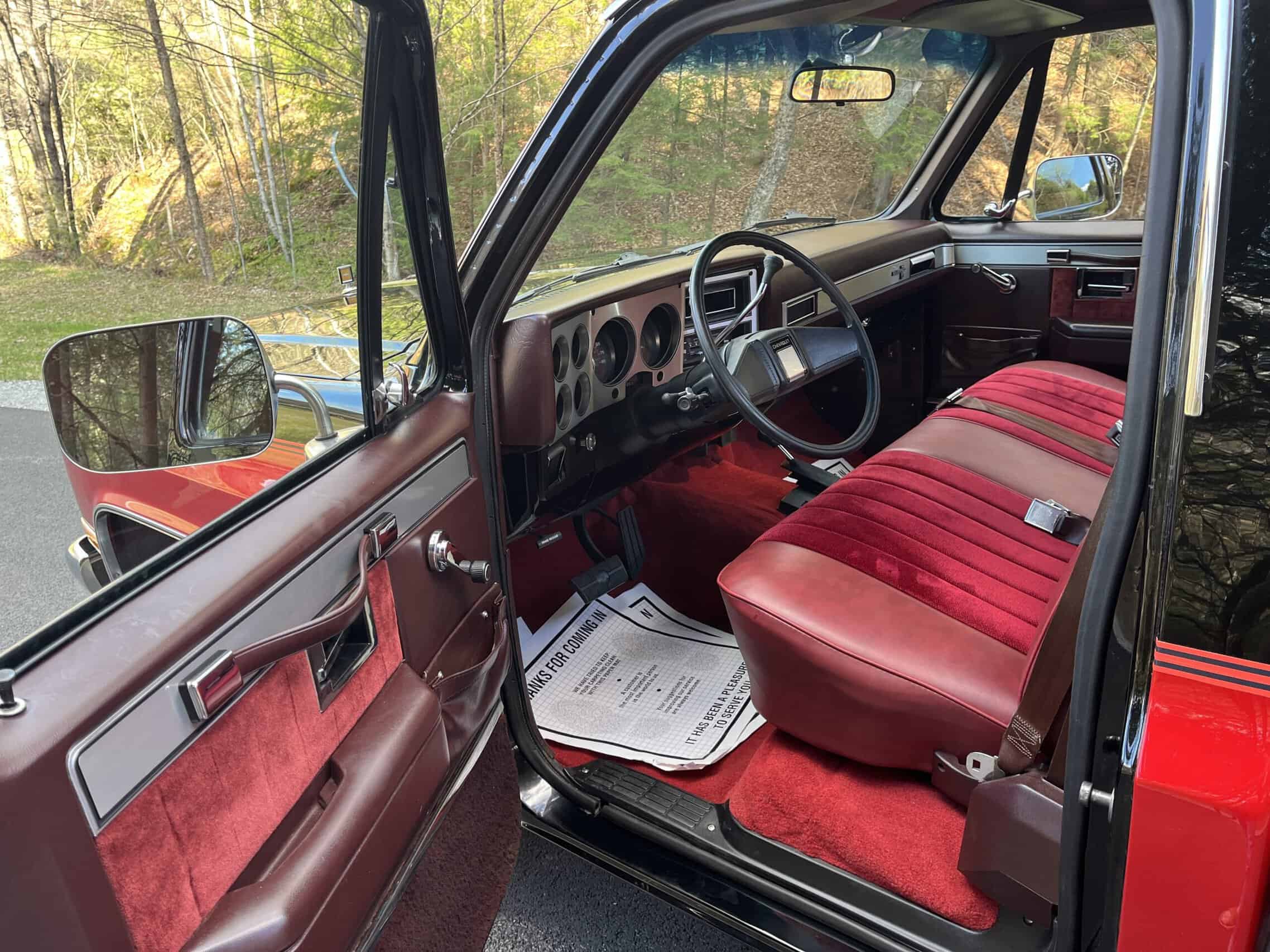 1986 Chevrolet SILVERADO — Interior view of a classic car with red bench seat and dashboard.