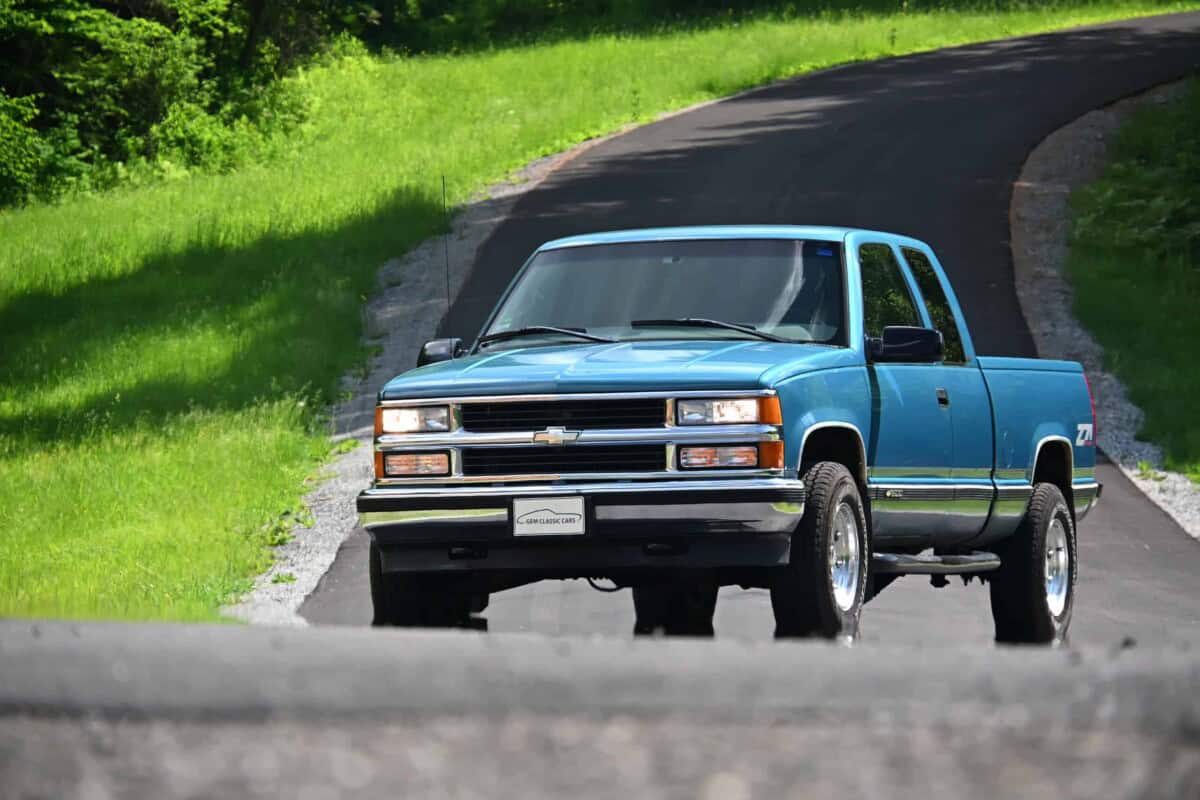 Blue classic pickup truck exterior shot on winding road.