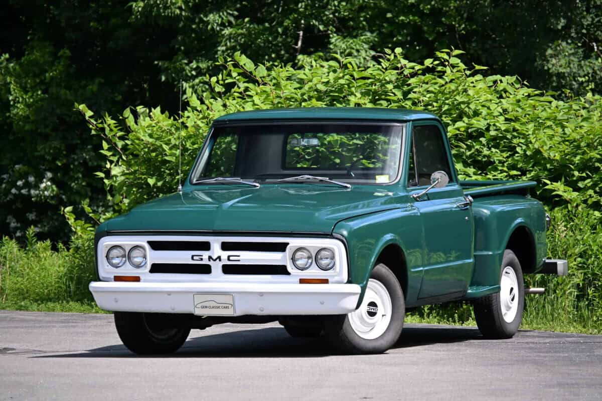Exterior view of a classic GMC pickup truck with green body and white wheels.