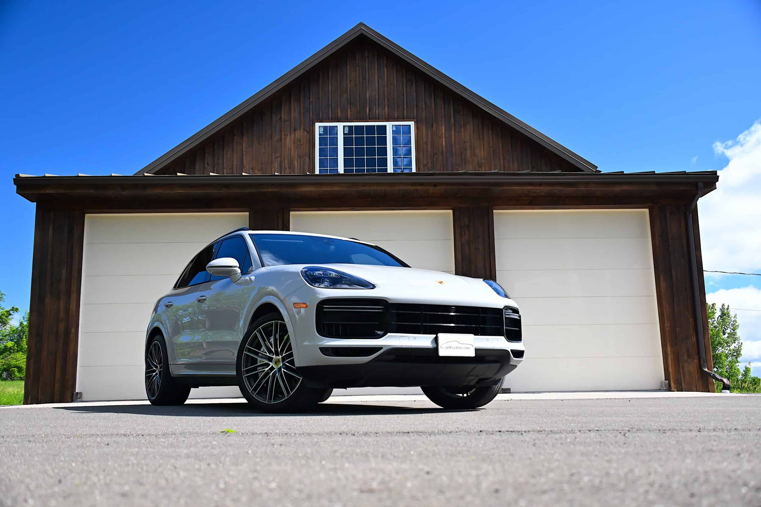 2022 Porsche Cayenne — Exterior shot of a classic car in front of a house with garage doors.
