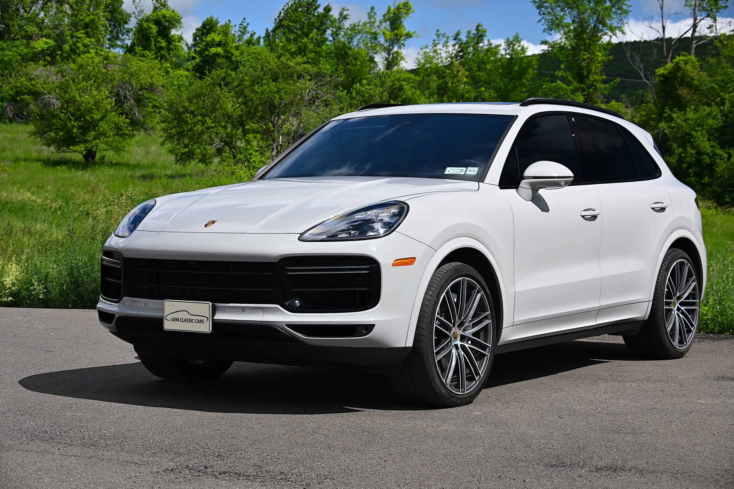 2022 Porsche Cayenne — White classic car SUV parked outdoors with green trees in background.