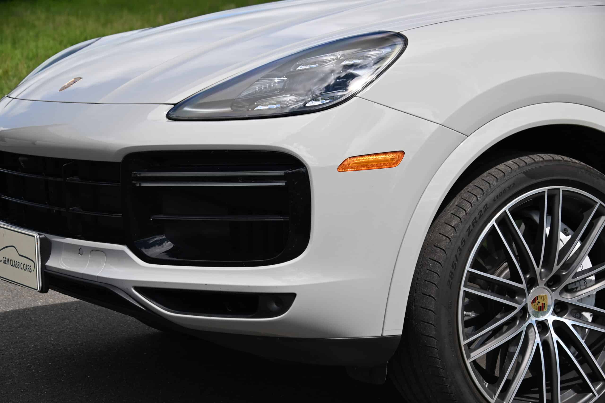 2022 Porsche Cayenne — Close-up of a white classic car's front with headlight and wheel.