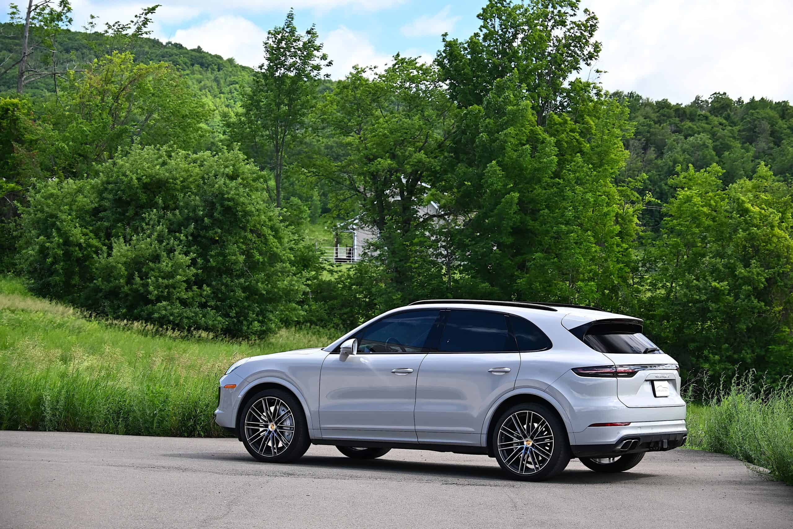 2022 Porsche Cayenne — Silver classic car exterior shot with lush trees and hills.