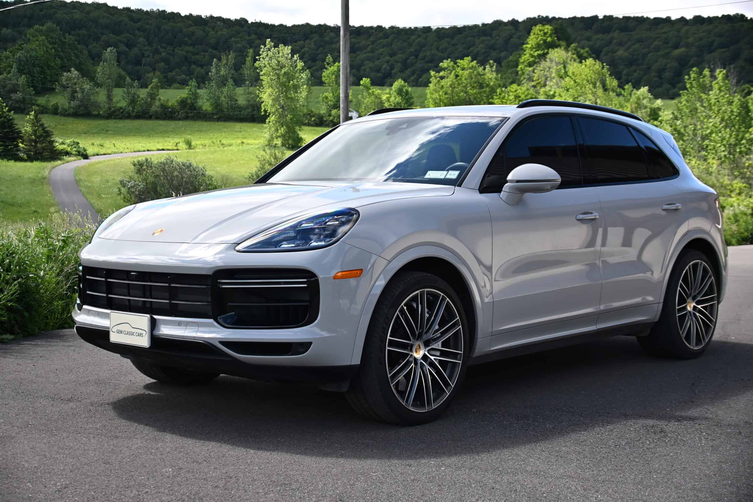 2022 Porsche Cayenne — Silver classic car SUV parked outdoors with green landscape.