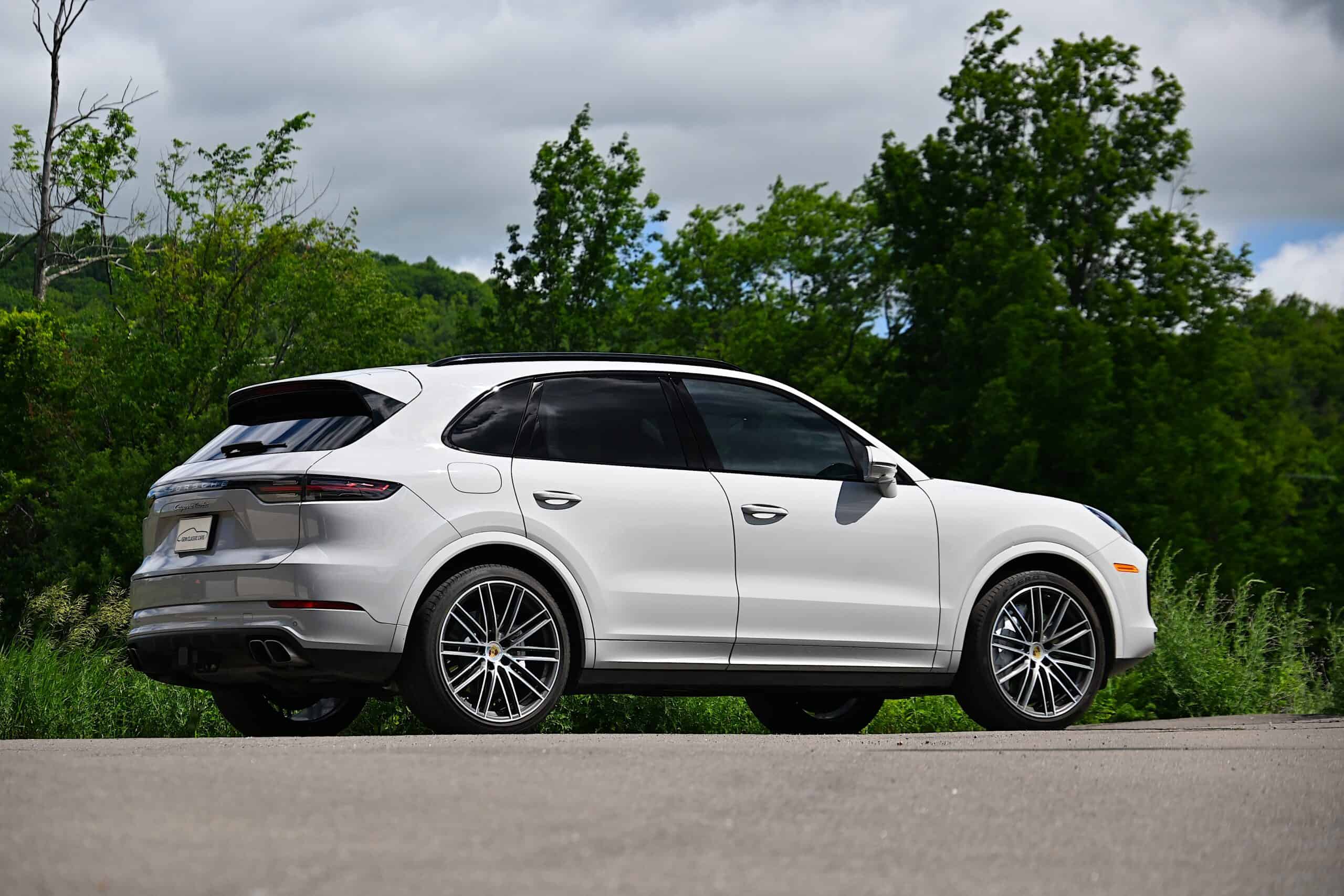 2022 Porsche Cayenne — White classic car SUV parked on road with green trees.