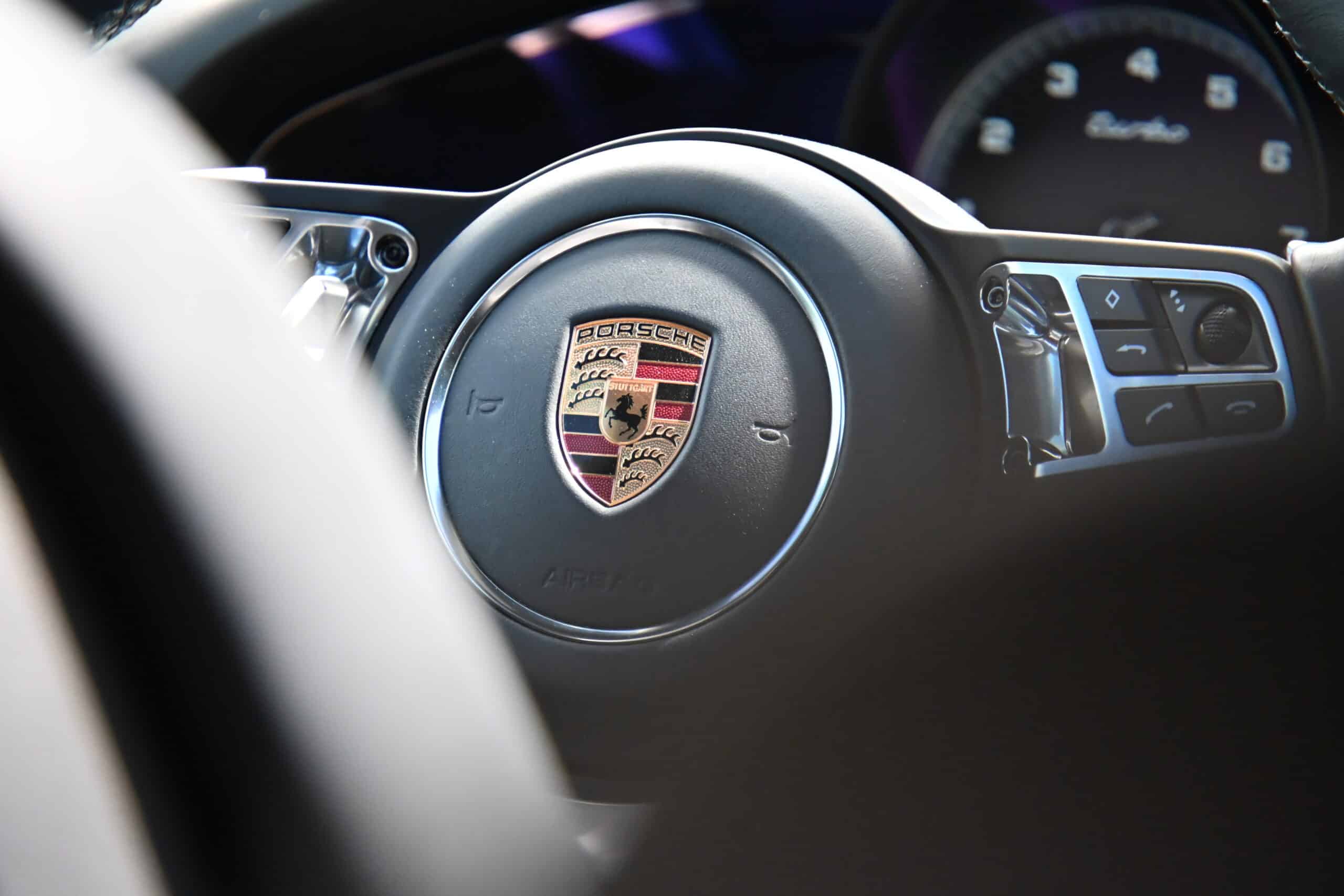 2022 Porsche Cayenne — Close-up of a classic car steering wheel with Porsche emblem.