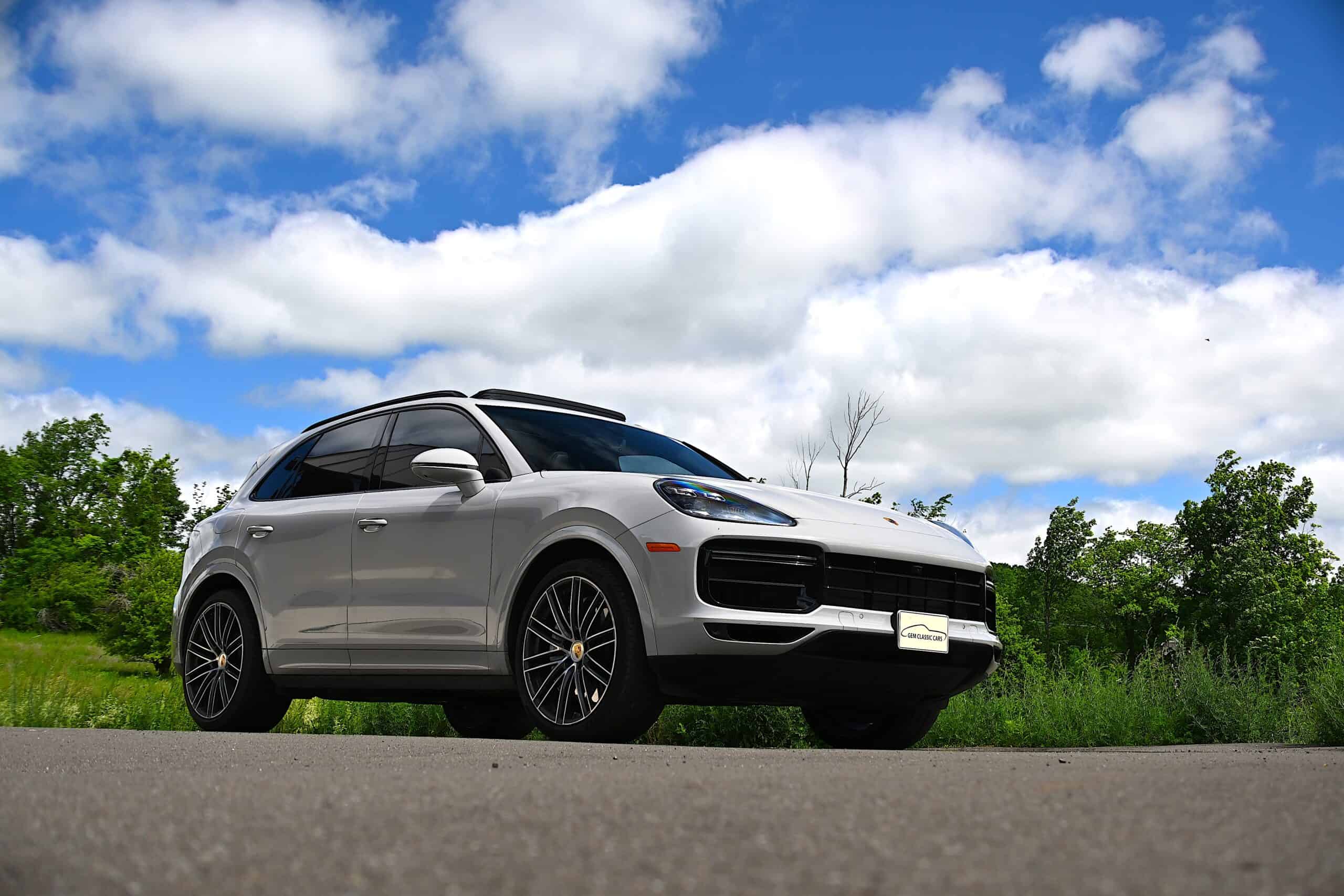 2022 Porsche Cayenne — Silver classic SUV parked outdoors with blue sky and clouds.