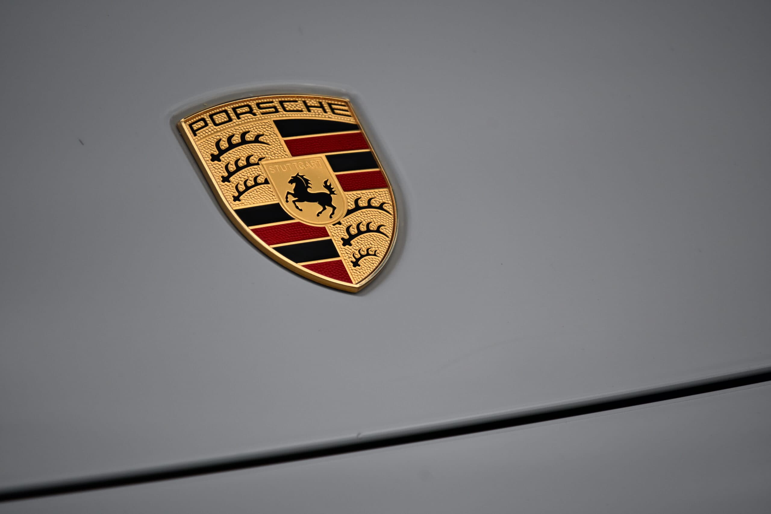 2022 Porsche Cayenne — Close-up of Porsche logo on classic car hood.
