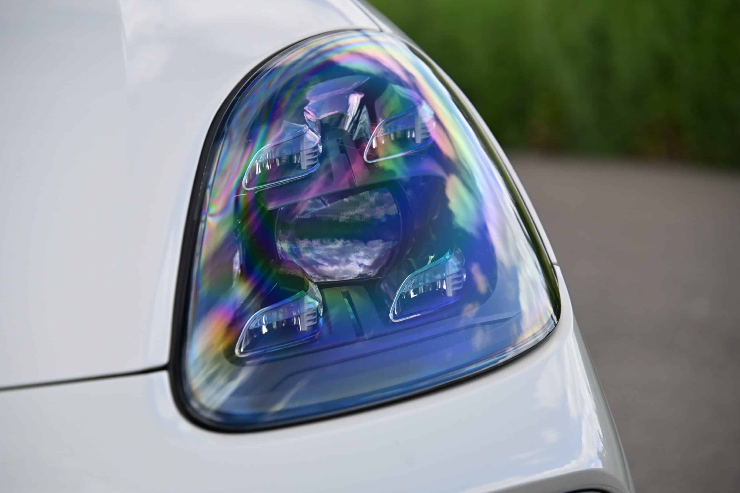 2022 Porsche Cayenne — Close-up of a classic car headlight with rainbow reflections.