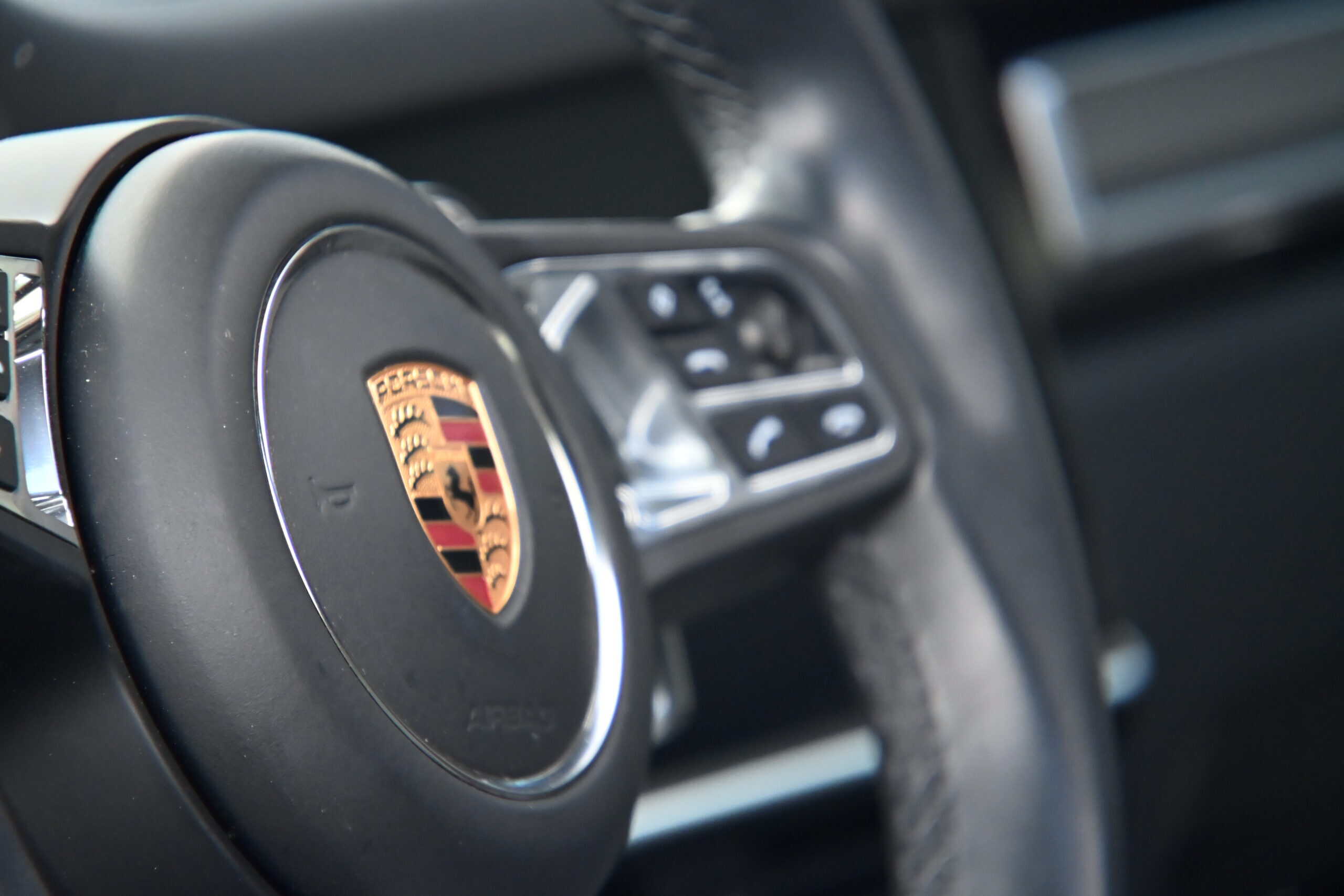 2022 Porsche Cayenne — Interior shot of a classic car steering wheel with Porsche logo.