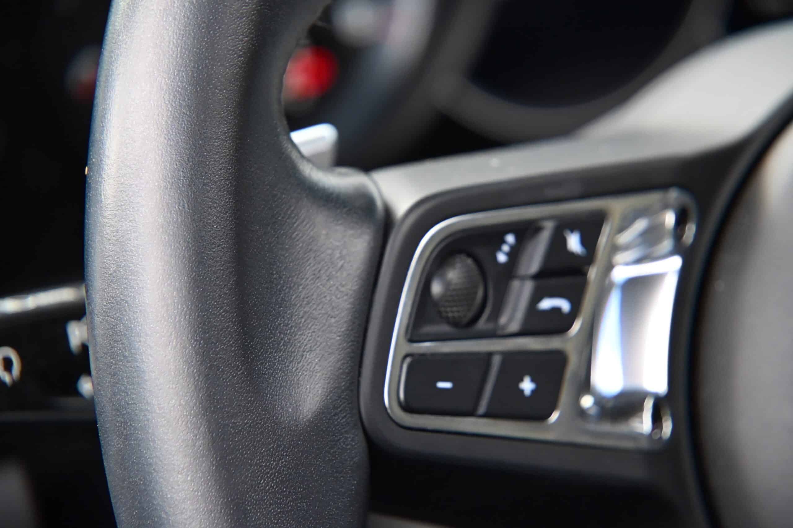 2022 Porsche Cayenne — Close-up of steering wheel with control buttons in a classic car.
