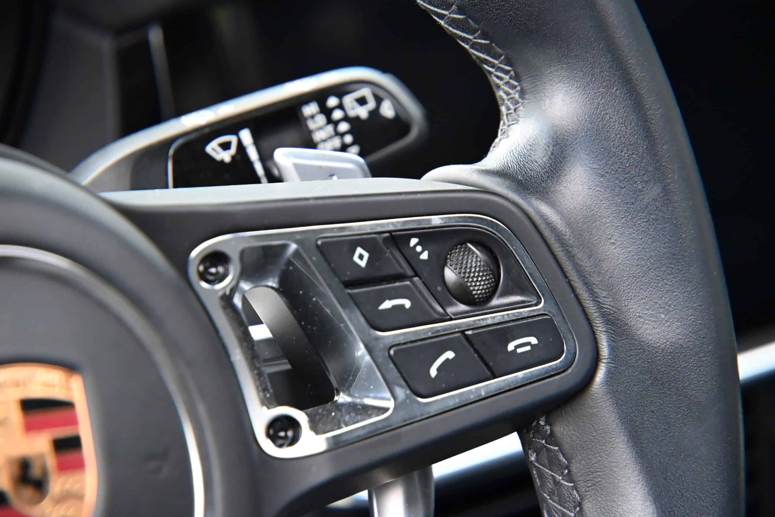 2022 Porsche Cayenne — Close-up of steering wheel with control buttons in a classic car.