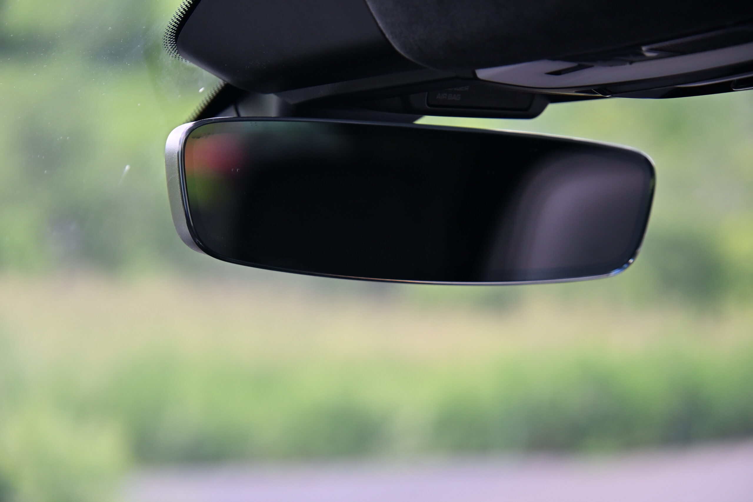 2022 Porsche Cayenne — Close-up of a classic car interior rearview mirror with blurred background.