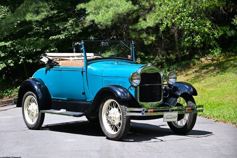 Blue classic car convertible with black fenders and white wheels.