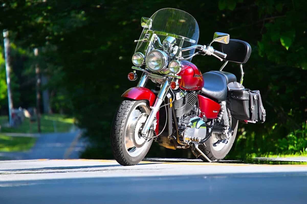 Red classic motorcycle with windshield and saddlebags on a sunny day.