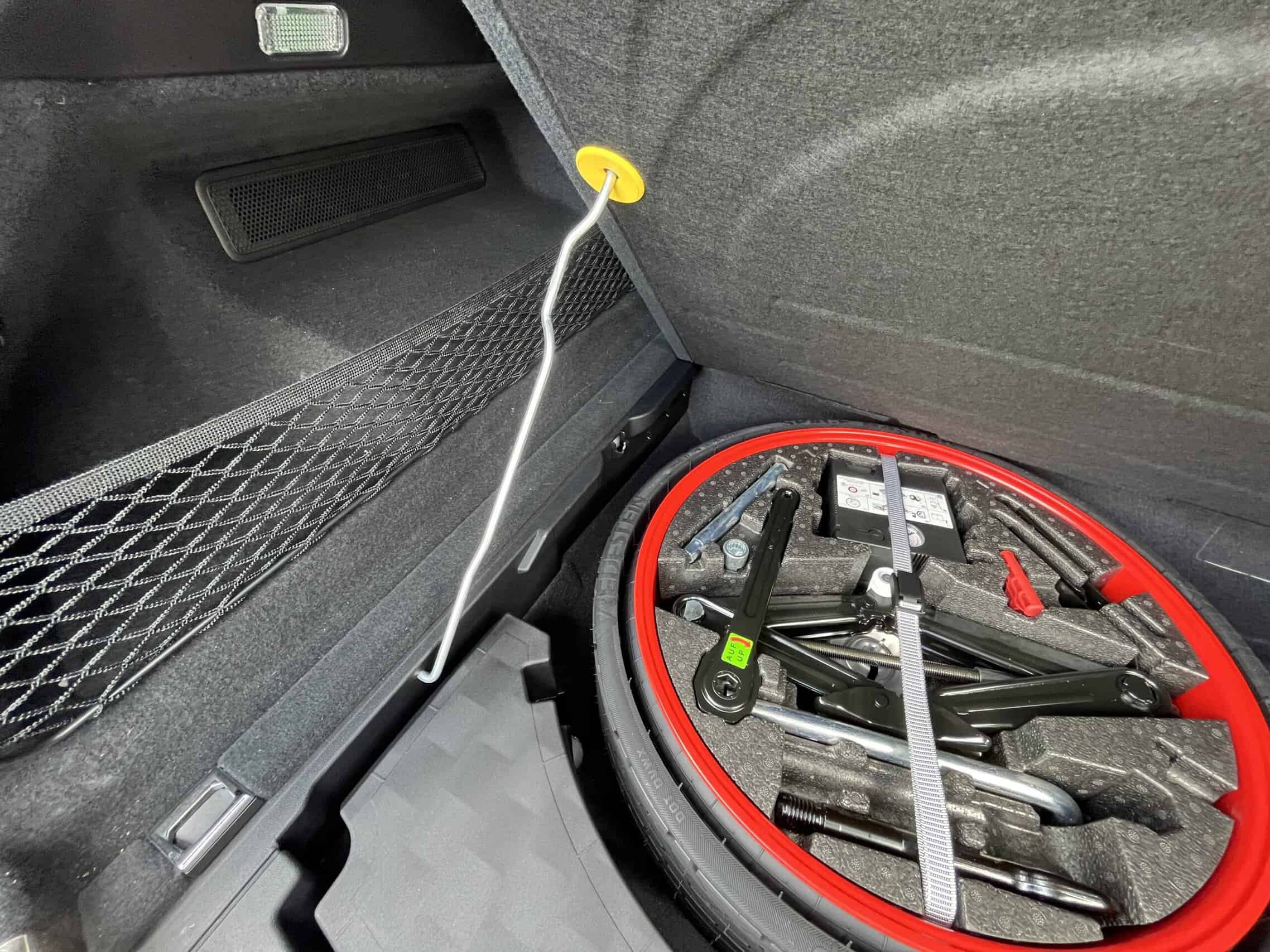 2022 Porsche Cayenne — Interior trunk of a classic car with jumper cables and tools.