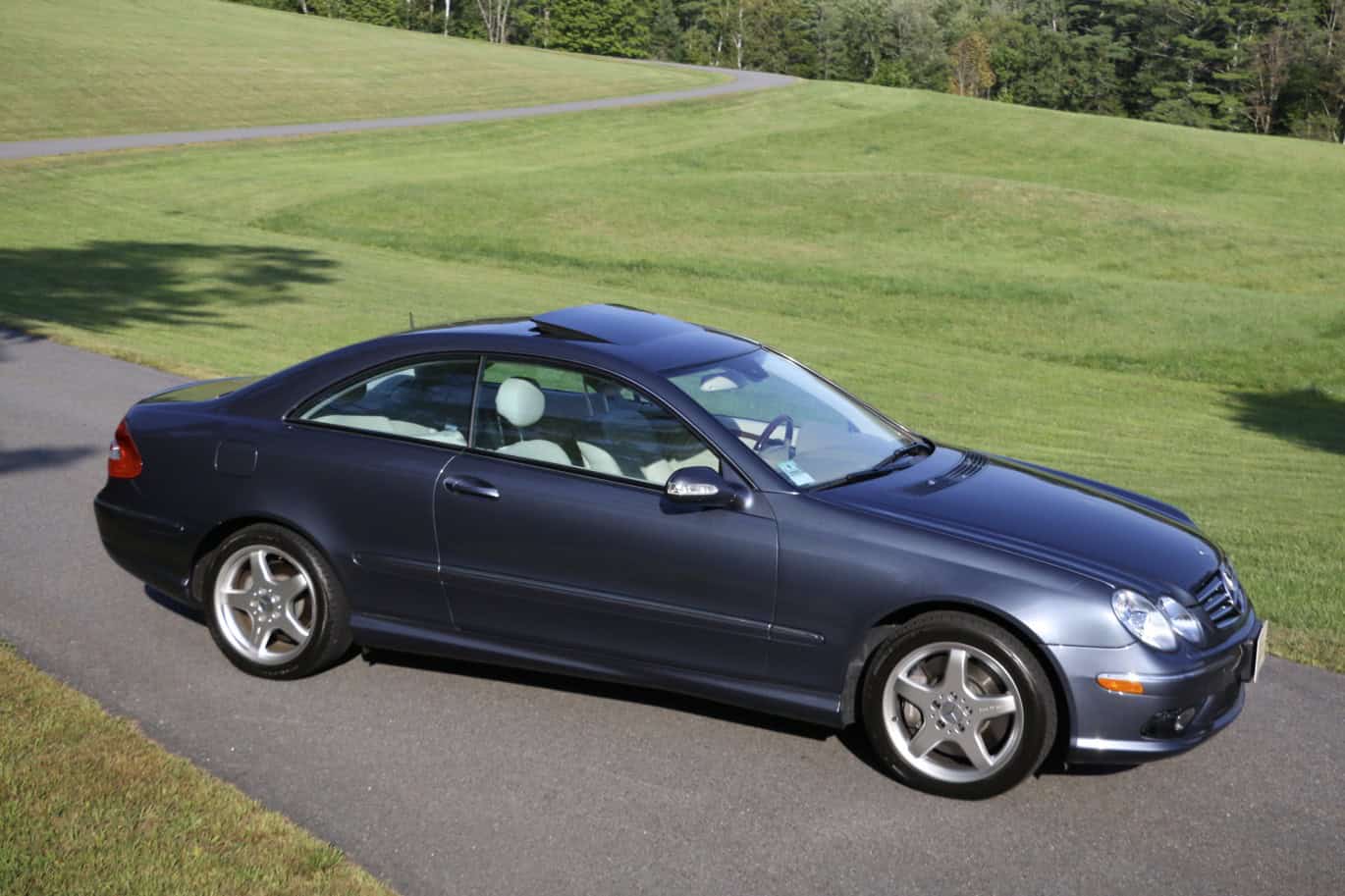 1999 Mercedes CLK500 — Dark blue classic car coupe parked on driveway with green lawn.