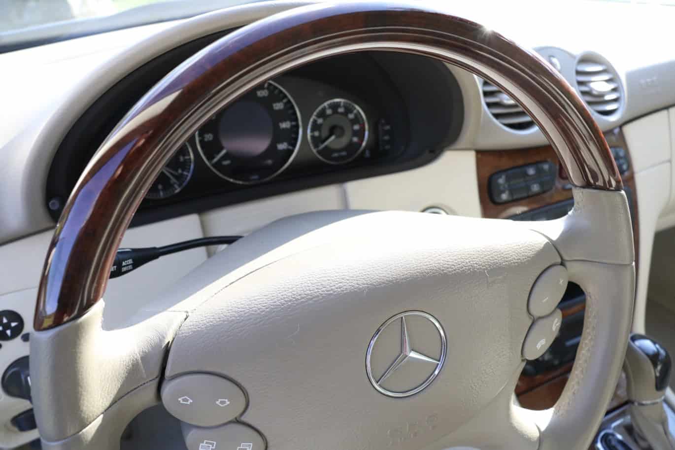 1999 Mercedes CLK500 — Close-up of classic car interior with steering wheel and dashboard.