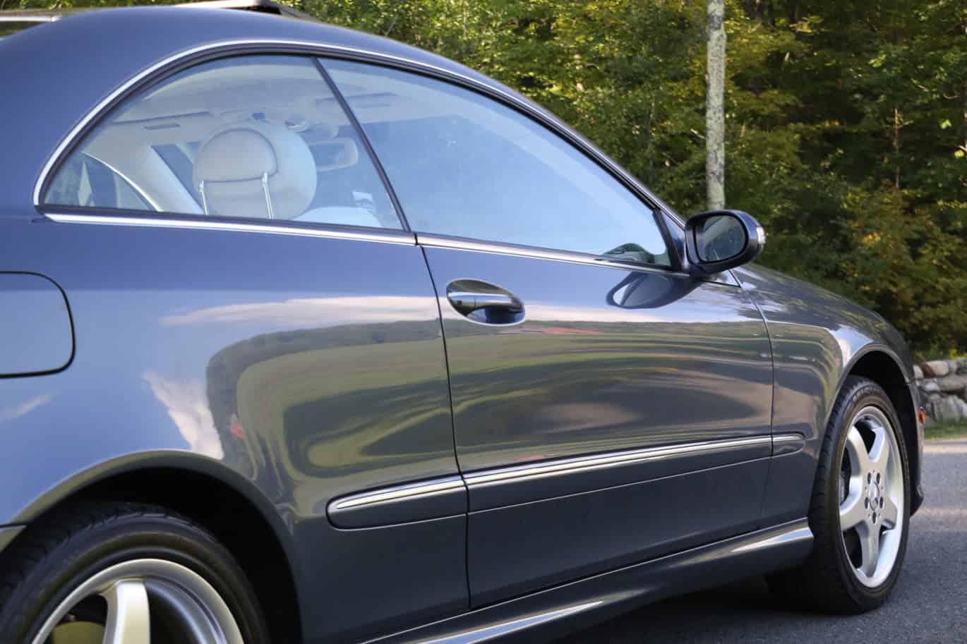 1999 Mercedes CLK500 — Side view of a classic car with a sleek dark blue body.