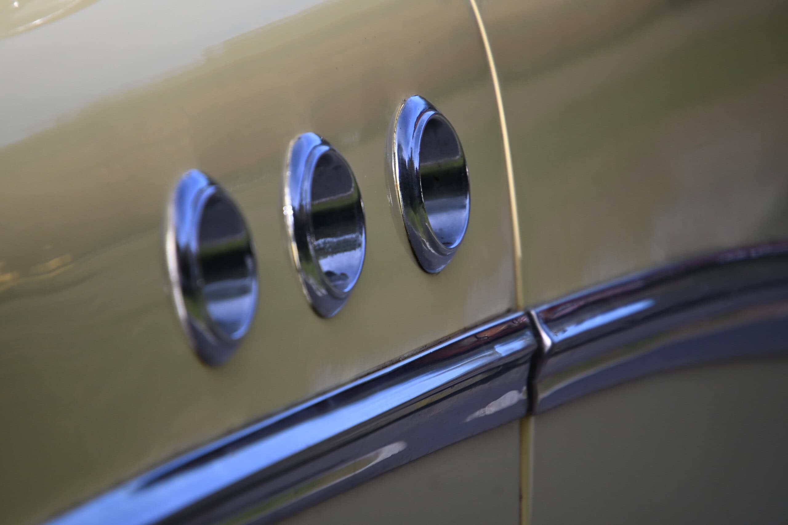1953 Buick special — Close-up of side vents on a classic car with gold paint.