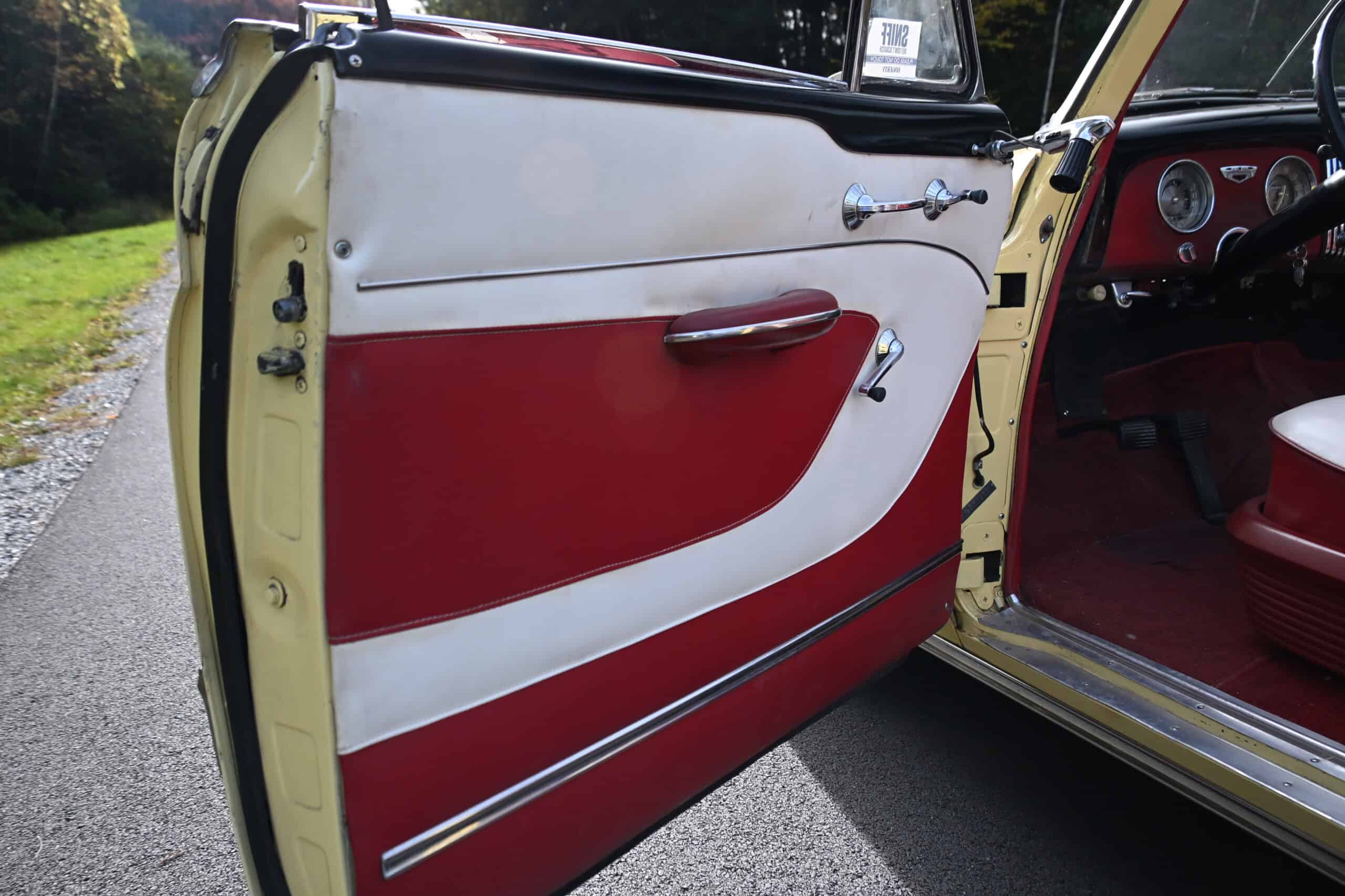 1953 Buick special — Close-up of classic car interior door with red and white design.