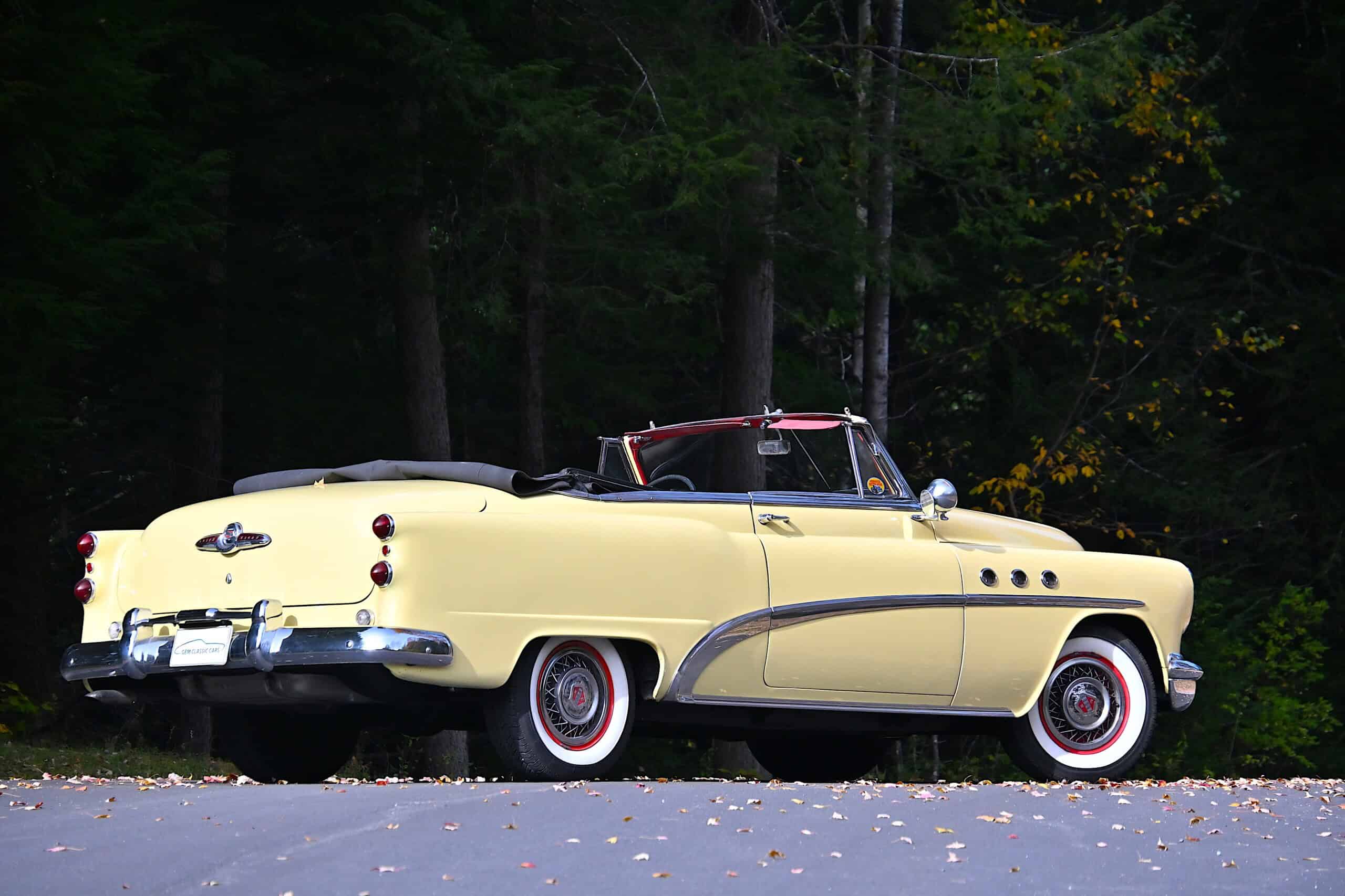 1953 Buick special — Yellow classic car convertible parked on the street with trees in background.
