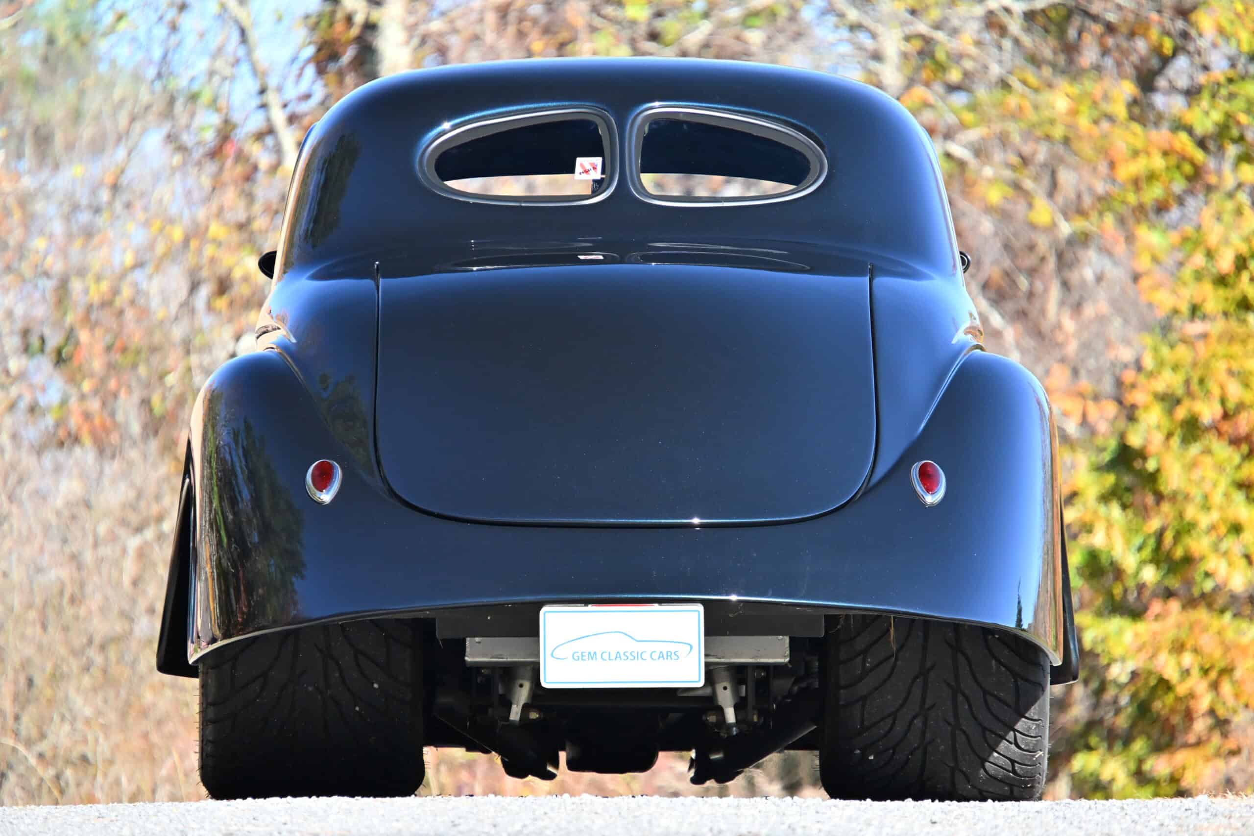 1941 Willys Custom Street Rod — Rear view of a black classic car with distinctive window design and rounded body.