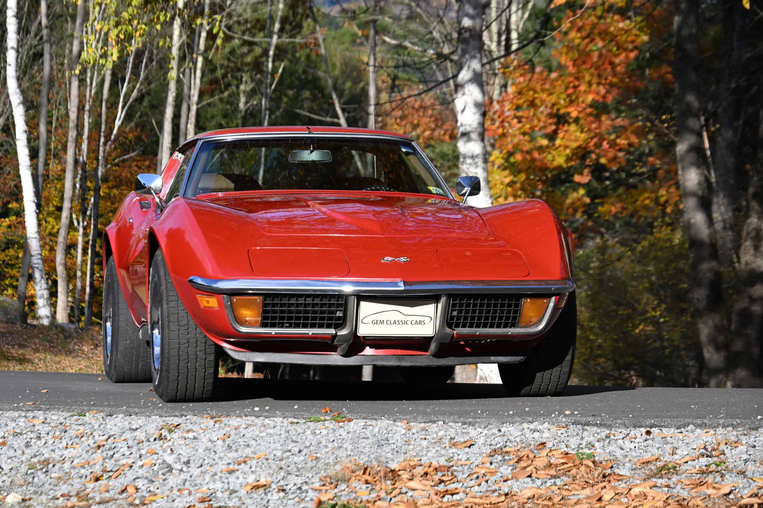 1972 Chevrolet corvette — Red classic car on road with autumn trees in background.