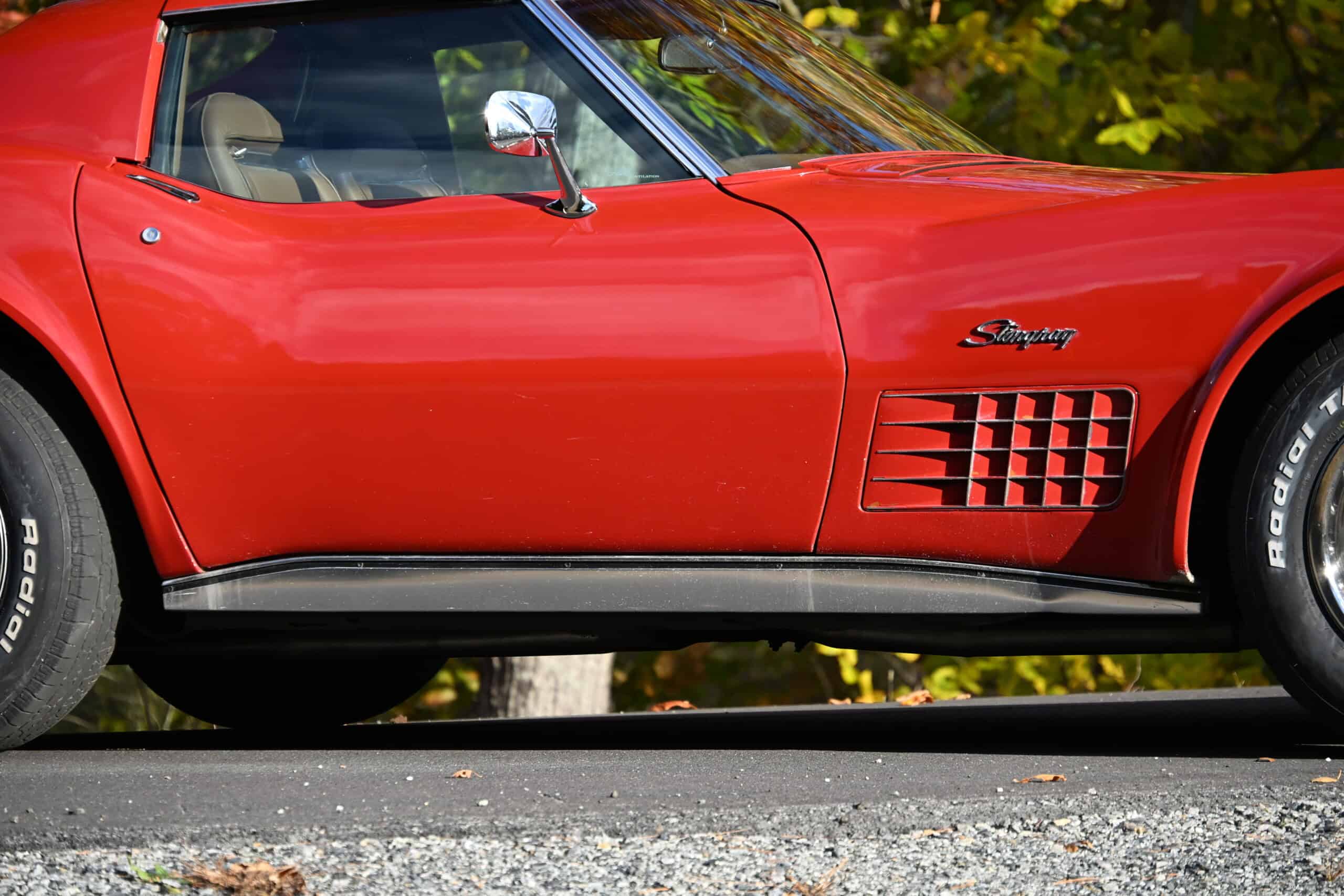 1972 Chevrolet corvette — Side view of a red classic car with vents and black side trim.