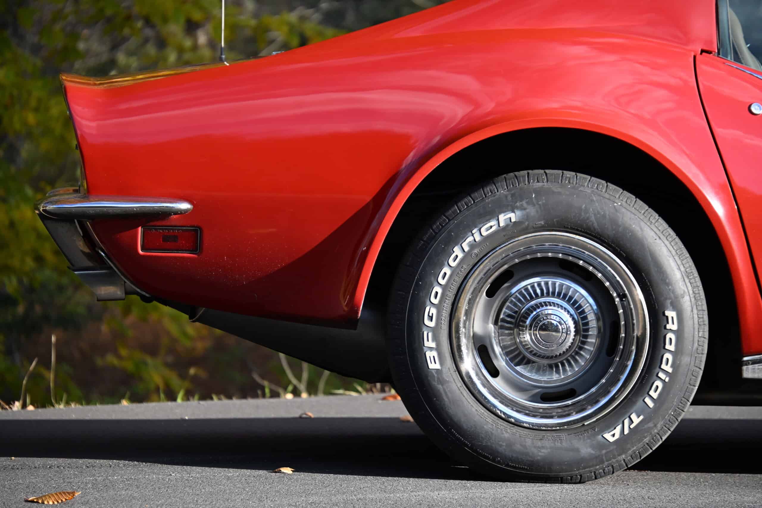 1972 Chevrolet corvette — Close-up of red classic car wheel and body with chrome hubcap.