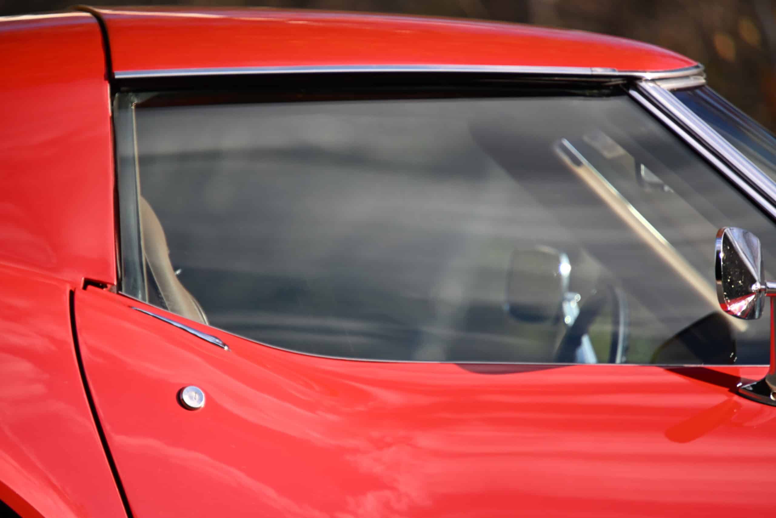 1972 Chevrolet corvette — Close-up of classic car with red exterior and side mirror.