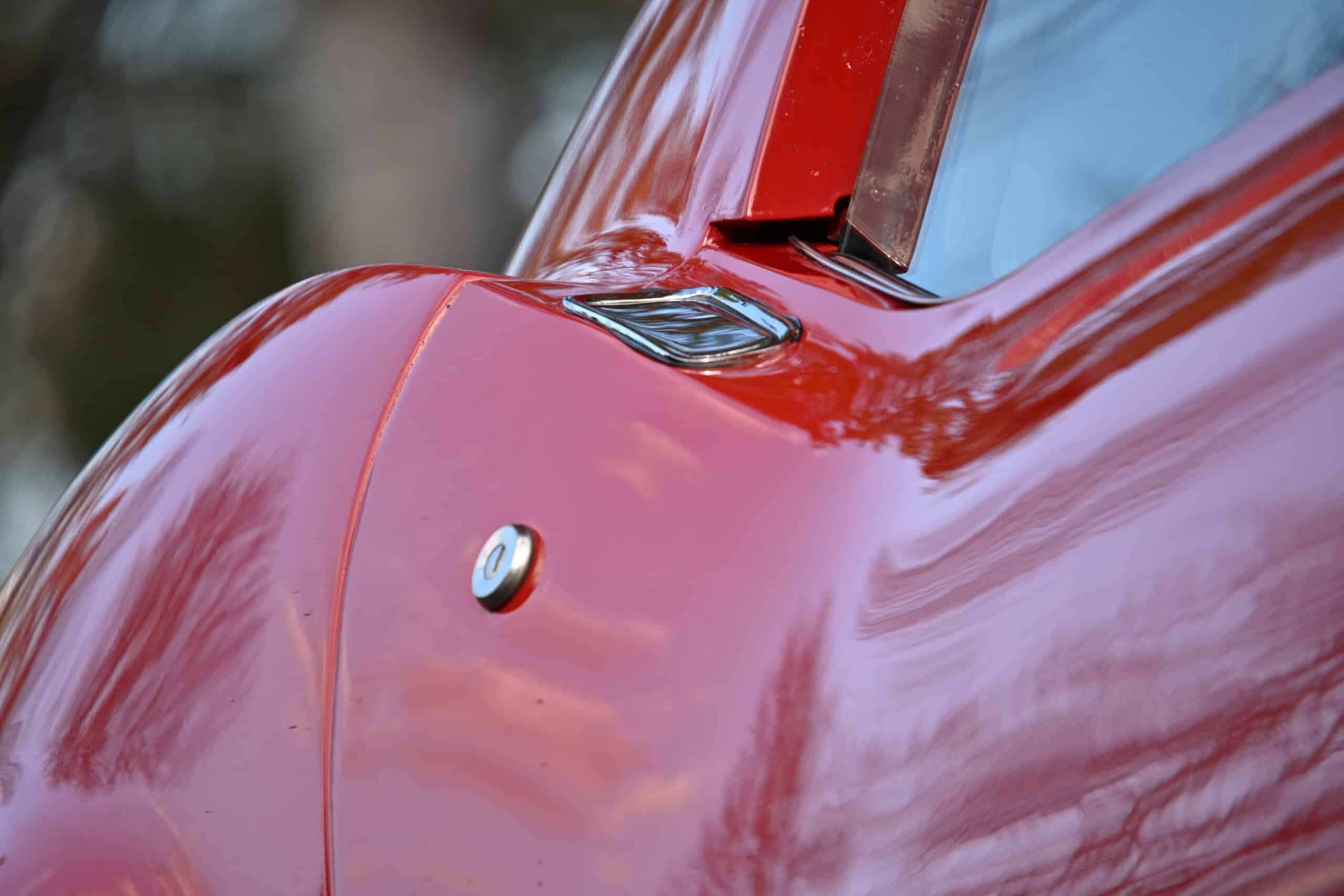 1972 Chevrolet corvette — Close-up of classic car body with shiny red paint and chrome details.