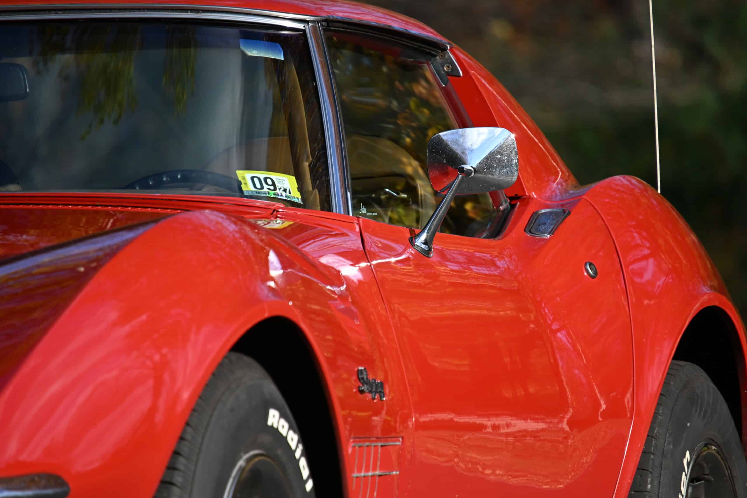 1972 Chevrolet corvette — Close-up of a classic car's front side with red paint and side mirror.