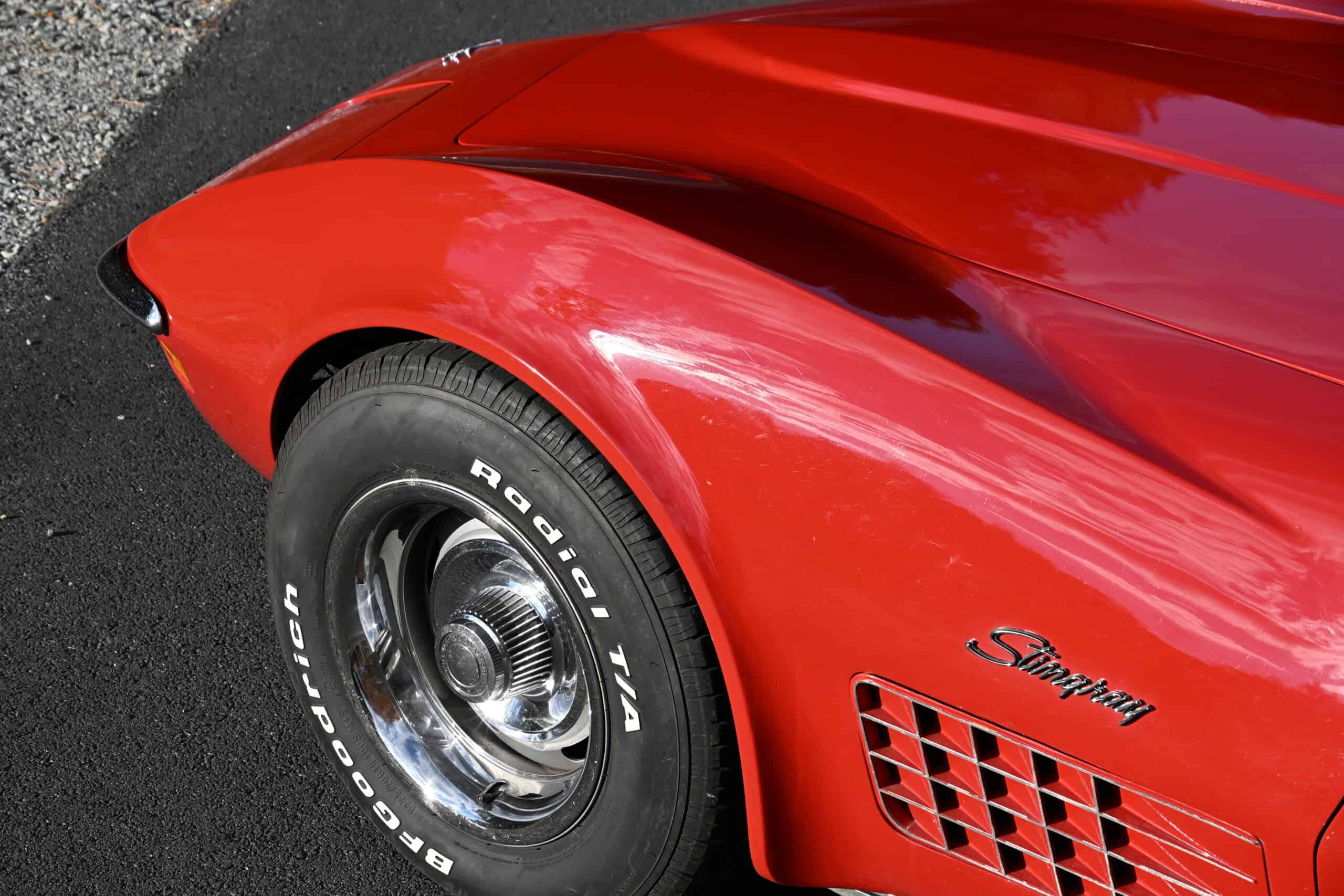 1972 Chevrolet corvette — Close-up of red classic car wheel and fender with vent details.