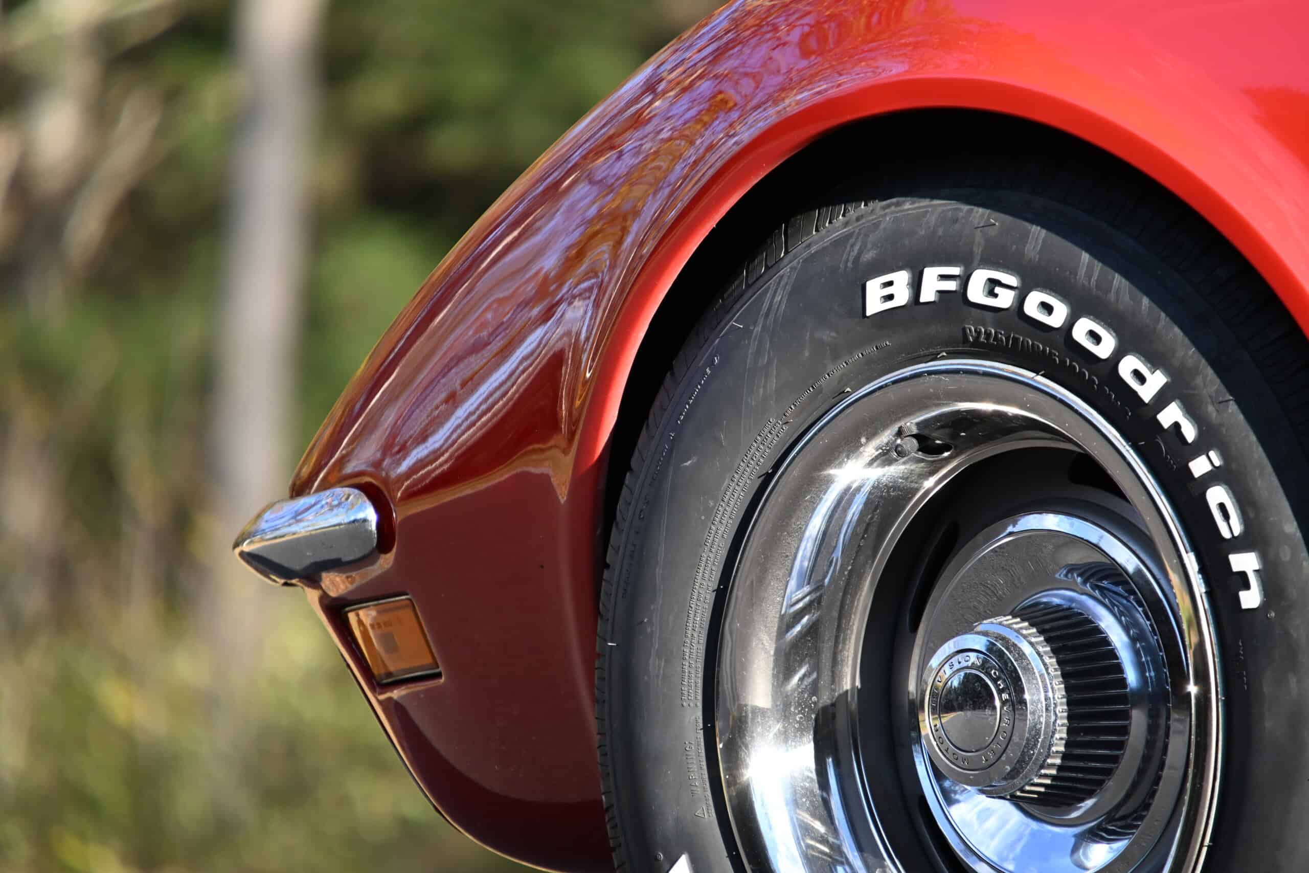 1972 Chevrolet corvette — Close-up of a classic car wheel and red fender with chrome hubcap.