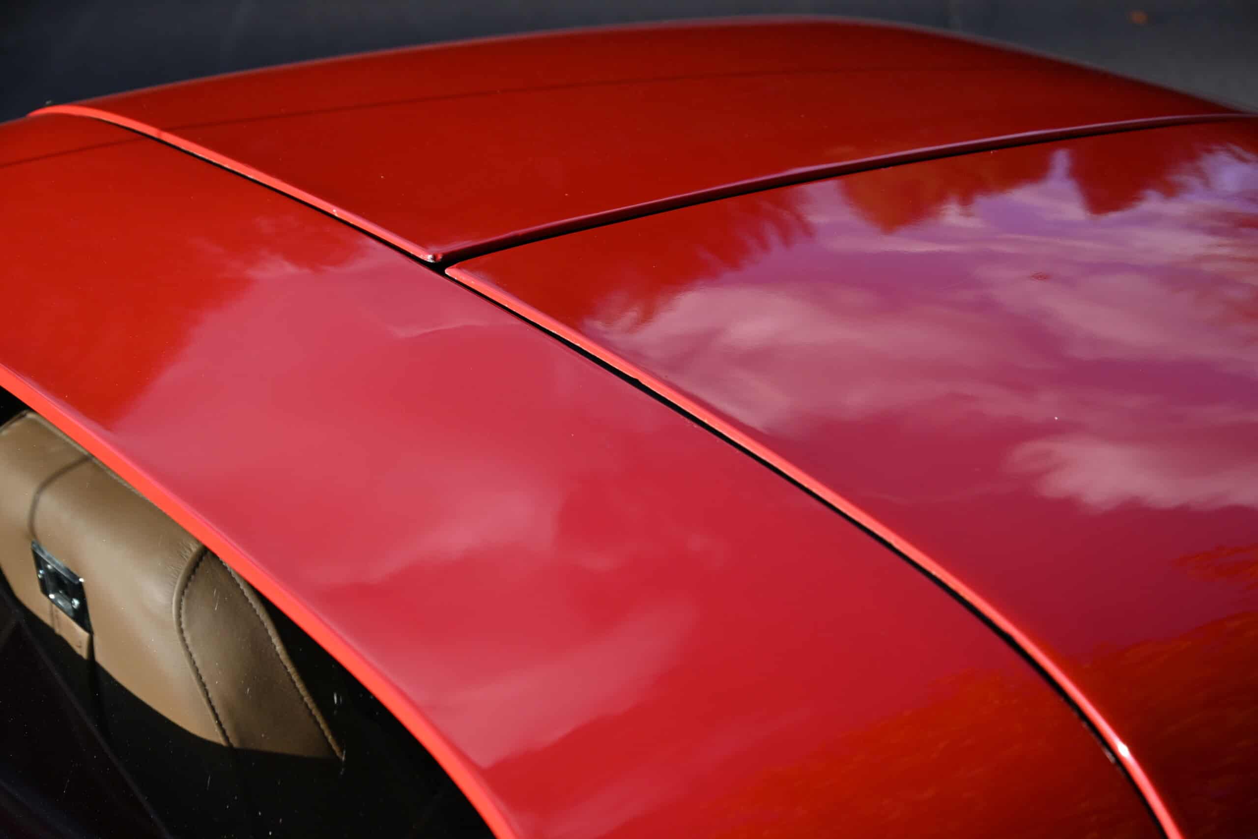 1972 Chevrolet corvette — Close-up of classic car roof with shiny red finish and reflections.